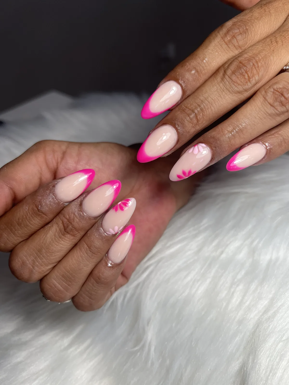 Hot pink French tips with hand-painted daisies on nude almond nails