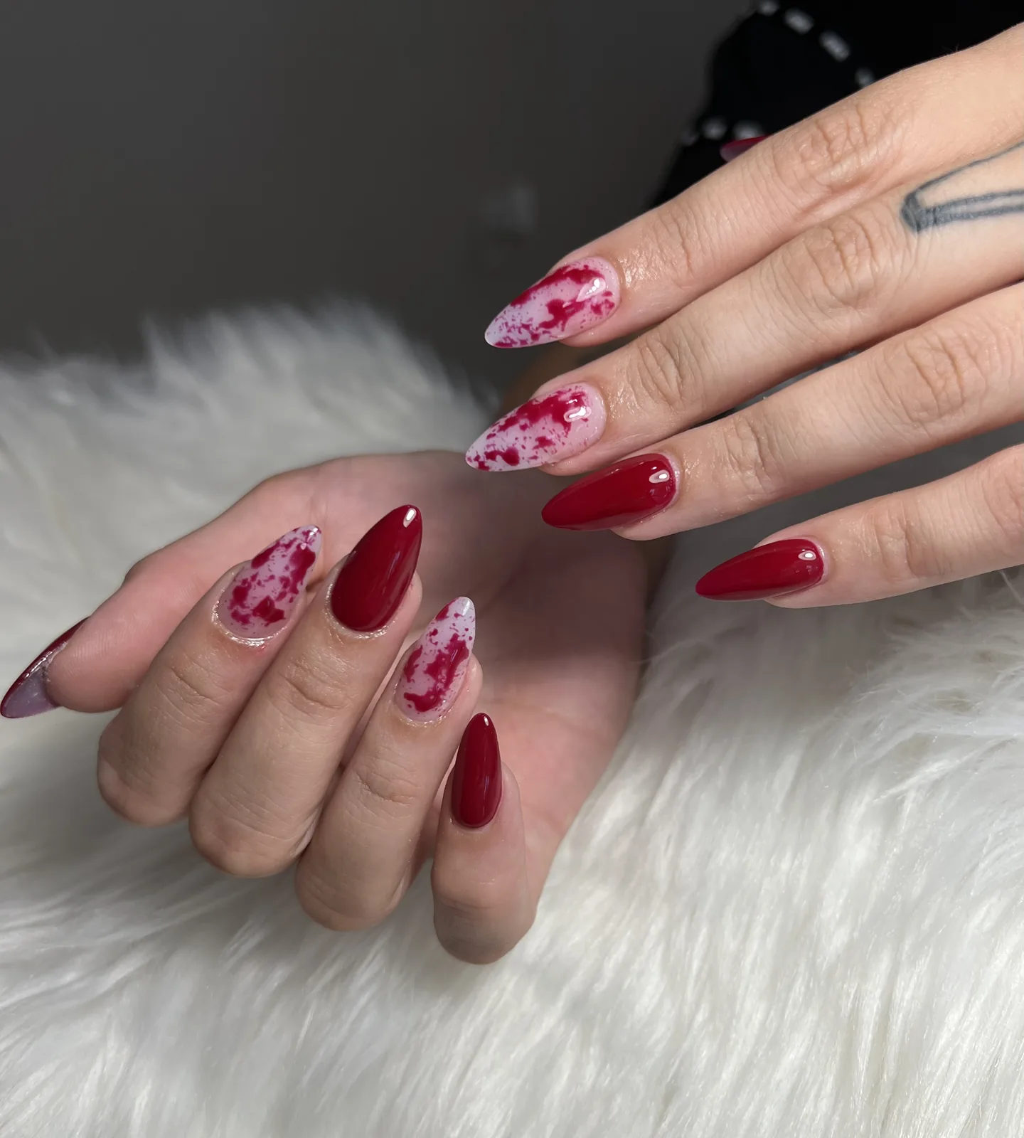Cherry red almond nails with white-and-crimson splatter accent
